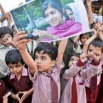 Un niño paquistaní levanta una imagen de Malala en una concentración a favor de ella, ayer en Karachi