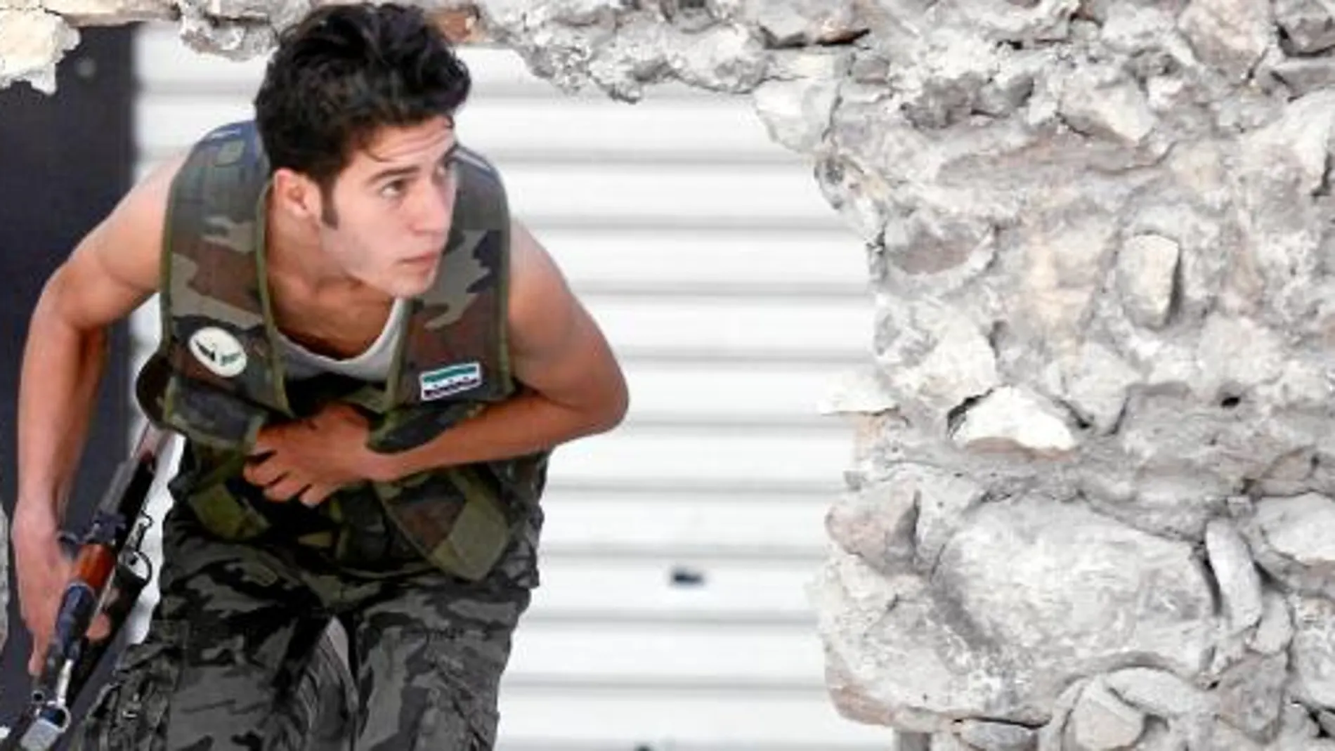 Un activista del Ejército Libre de Siria (ELS) corre para cubrirse durante los fuertes choques armados en el barrio de Saladino de Alepo. El miércoles las tropas leales a Asad lanzaron una ofensiva en este bastión rebelde en la capital financiera del país