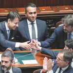 El primer ministro, Giuseppe Conte (izq.), junto a Luigi di Maio, es felicitado por los ministros tras presentar su programa de gobierno
