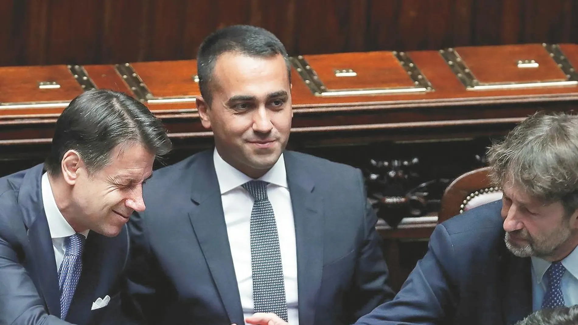 El primer ministro, Giuseppe Conte (izq.), junto a Luigi di Maio, es felicitado por los ministros tras presentar su programa de gobierno