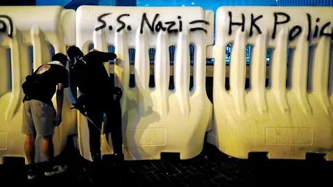 Dos jóvenes activistas hacen una pintada contra la Policía de Hong Kong, a la que califica de nazi / Efe