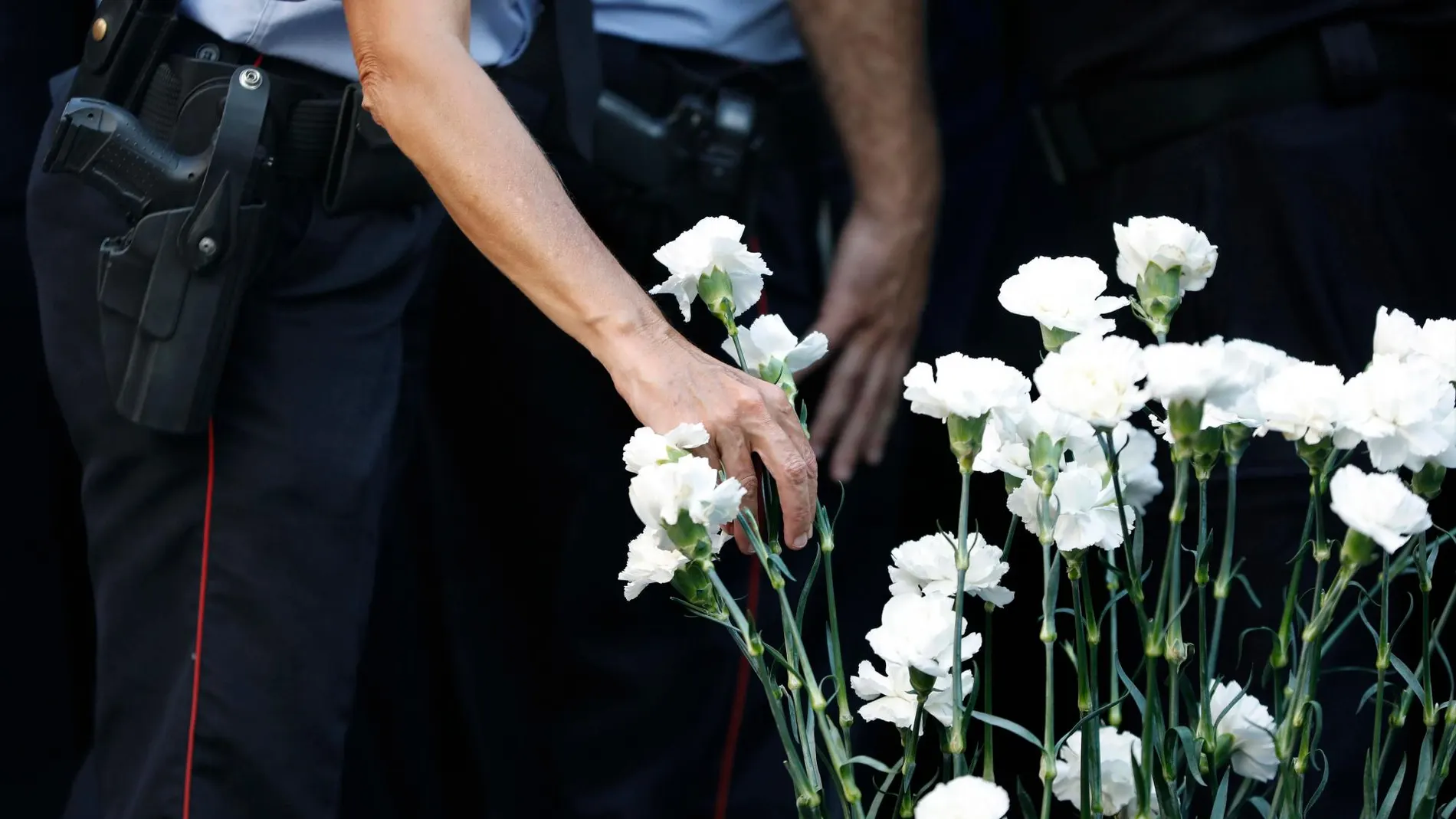 Miembros de los Mossos d’Esquadra colocando claveles blancos en honor a las víctimas
