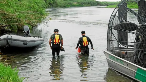 Dos de los submarinistas del equipo de rastreo en una de las orillas del río / Reuters