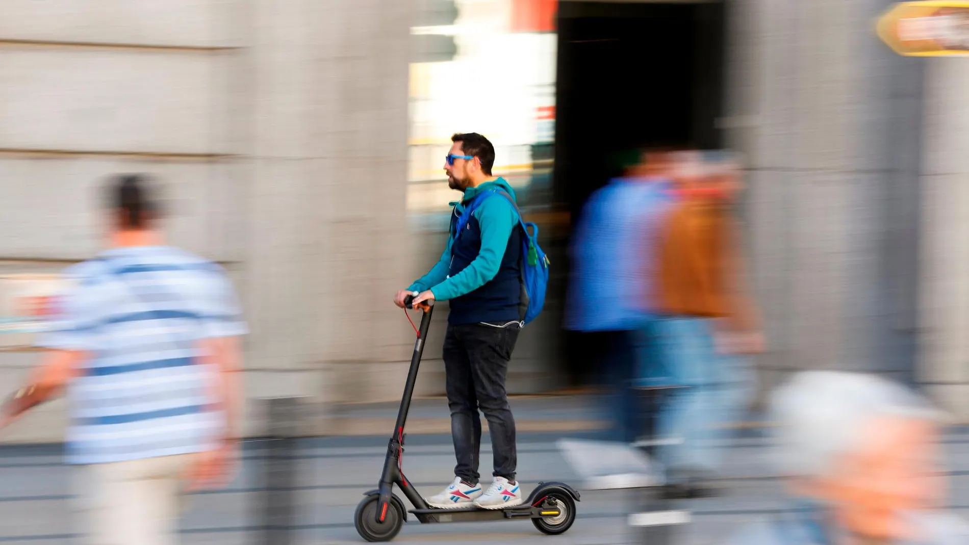 Hombre conduciendo un patinete eléctrico por la calle