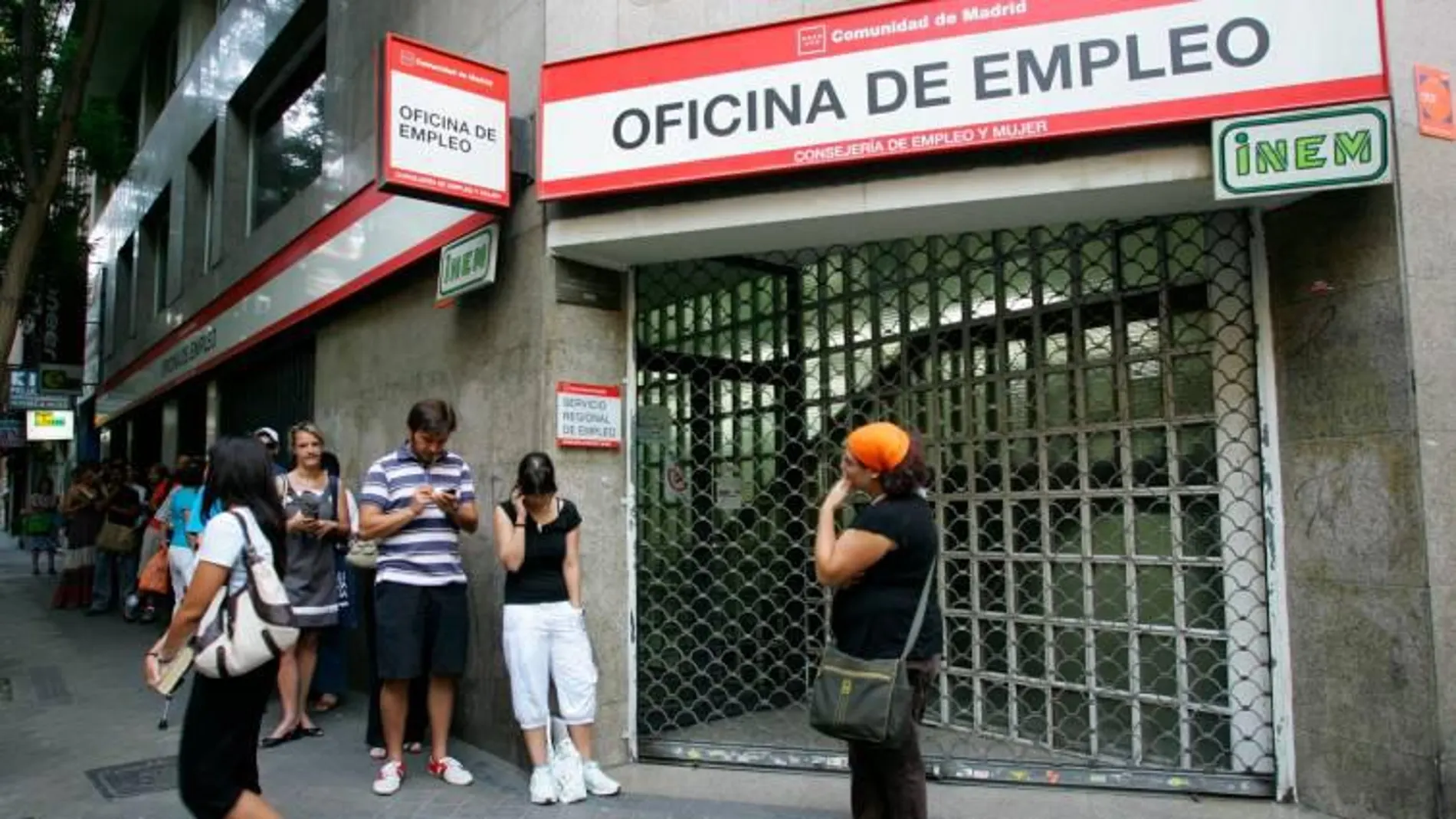 Varias personas esperan a las puertas de una oficina de empleo