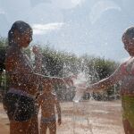 Unas niñas se refrescan en una fuente