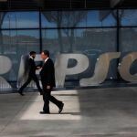 Dos hombres caminan junto a las oficinas centrales de Repsol en Madrid