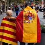 Dos personas pasean en Barcelona con una bandera de España y una de Cataluña