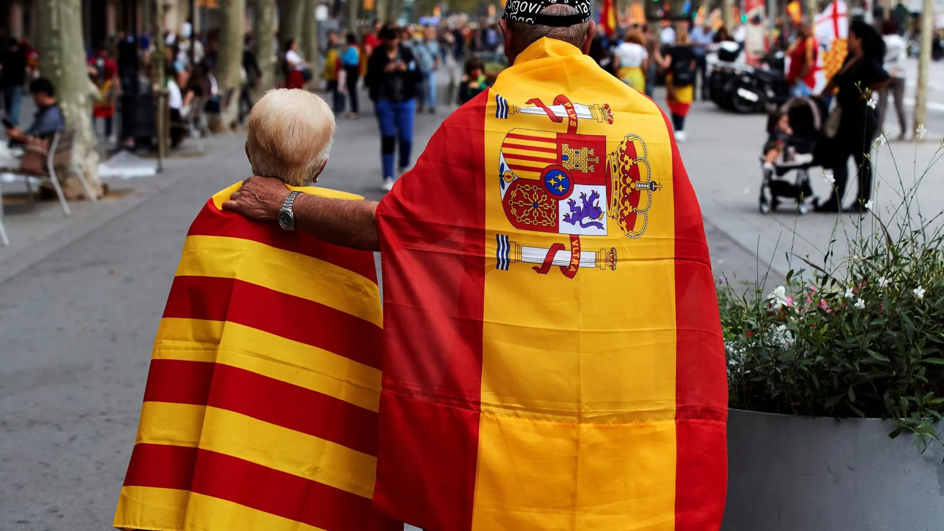 Dos personas pasean en Barcelona con una bandera de España y una de Cataluña