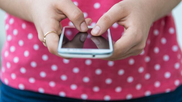 Una joven sostiene su móvil en la mano