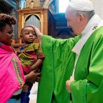 El Papa acaricia a un niño después de la misa por los refugiados, a la que asistieron familias de migrantes