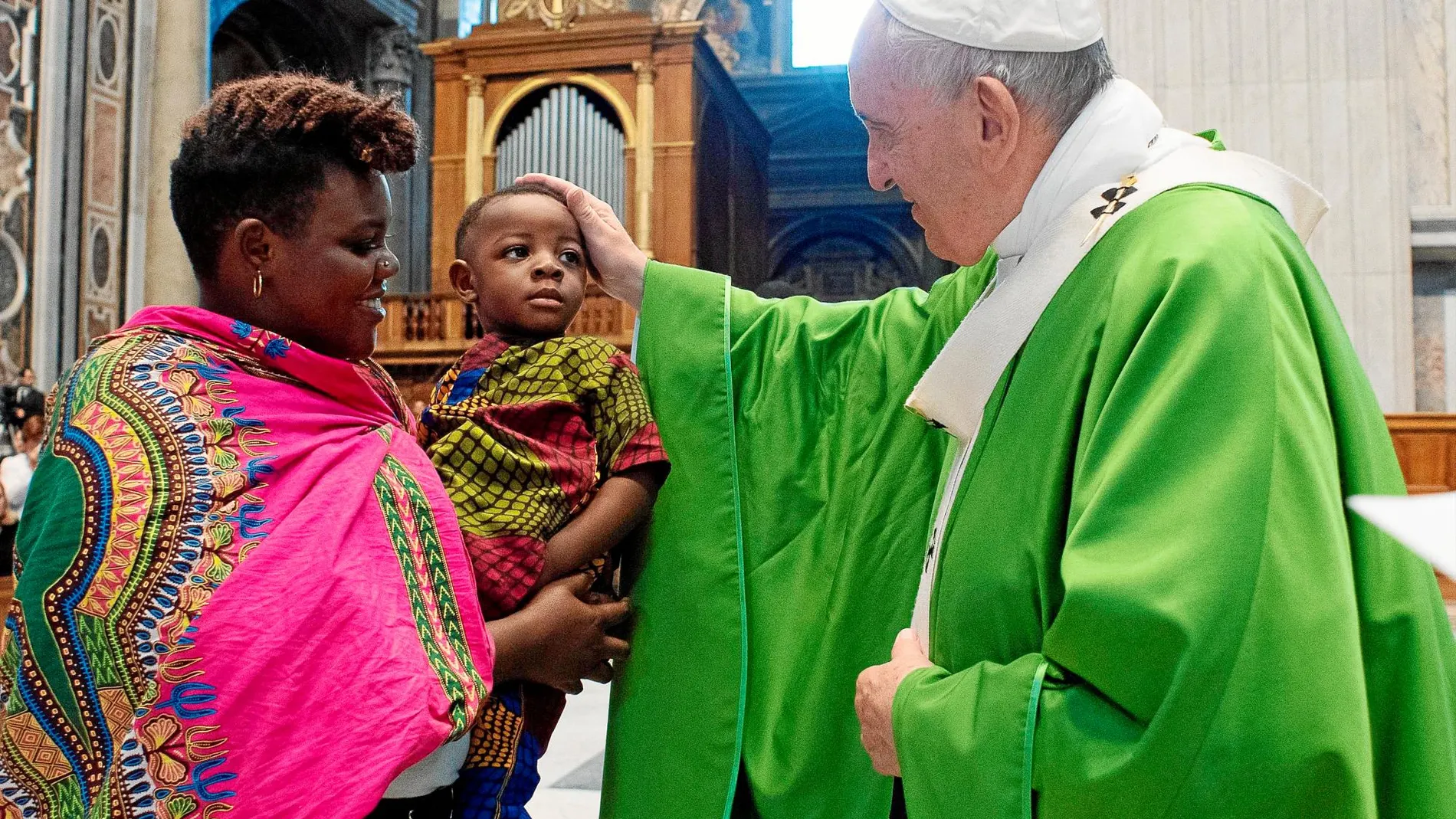 El Papa acaricia a un niño después de la misa por los refugiados, a la que asistieron familias de migrantes