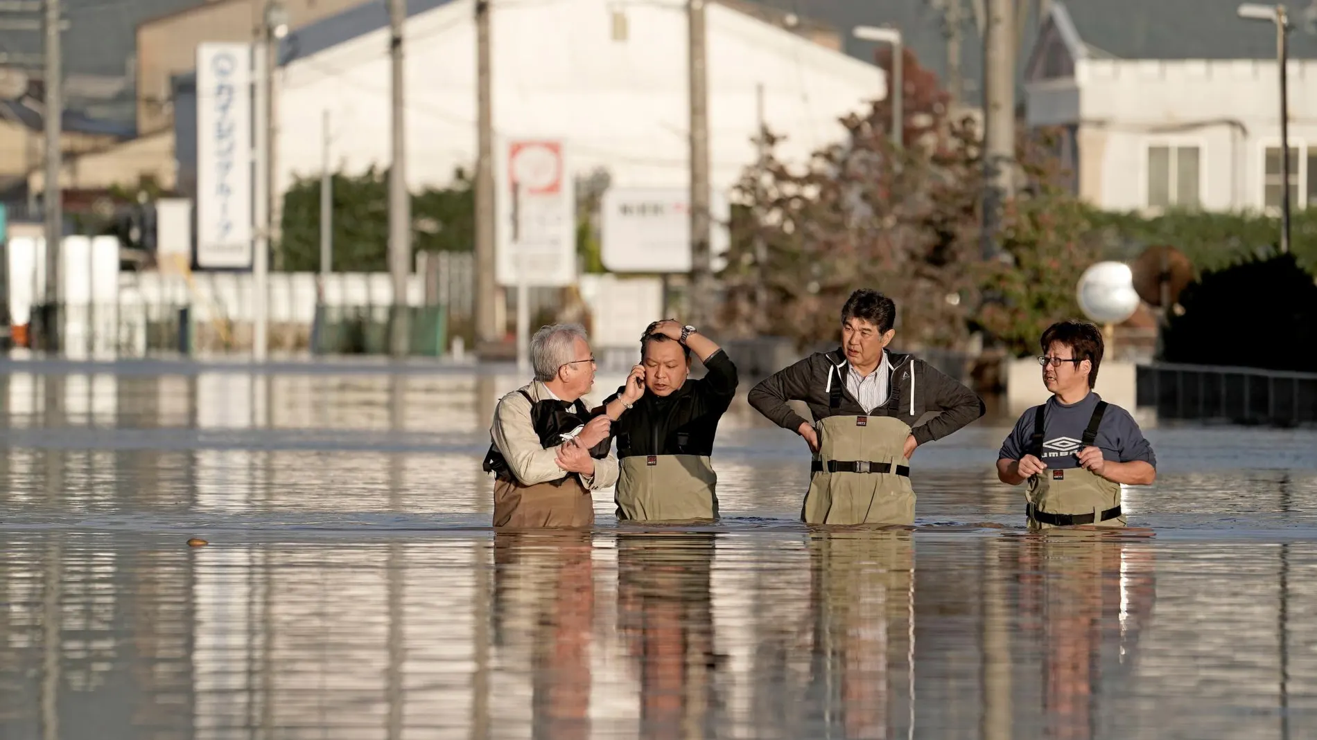 Unos trabajadores intentan salir de una zona inundada en la prefectura de Nagano, en Japón.