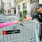 Una mujer ayer en Barcelona entrega unas rosas a un policía en una imagen agridulce ya que lo tiene que hacer detrás de unas verjas colocadas allí desde los disturbios