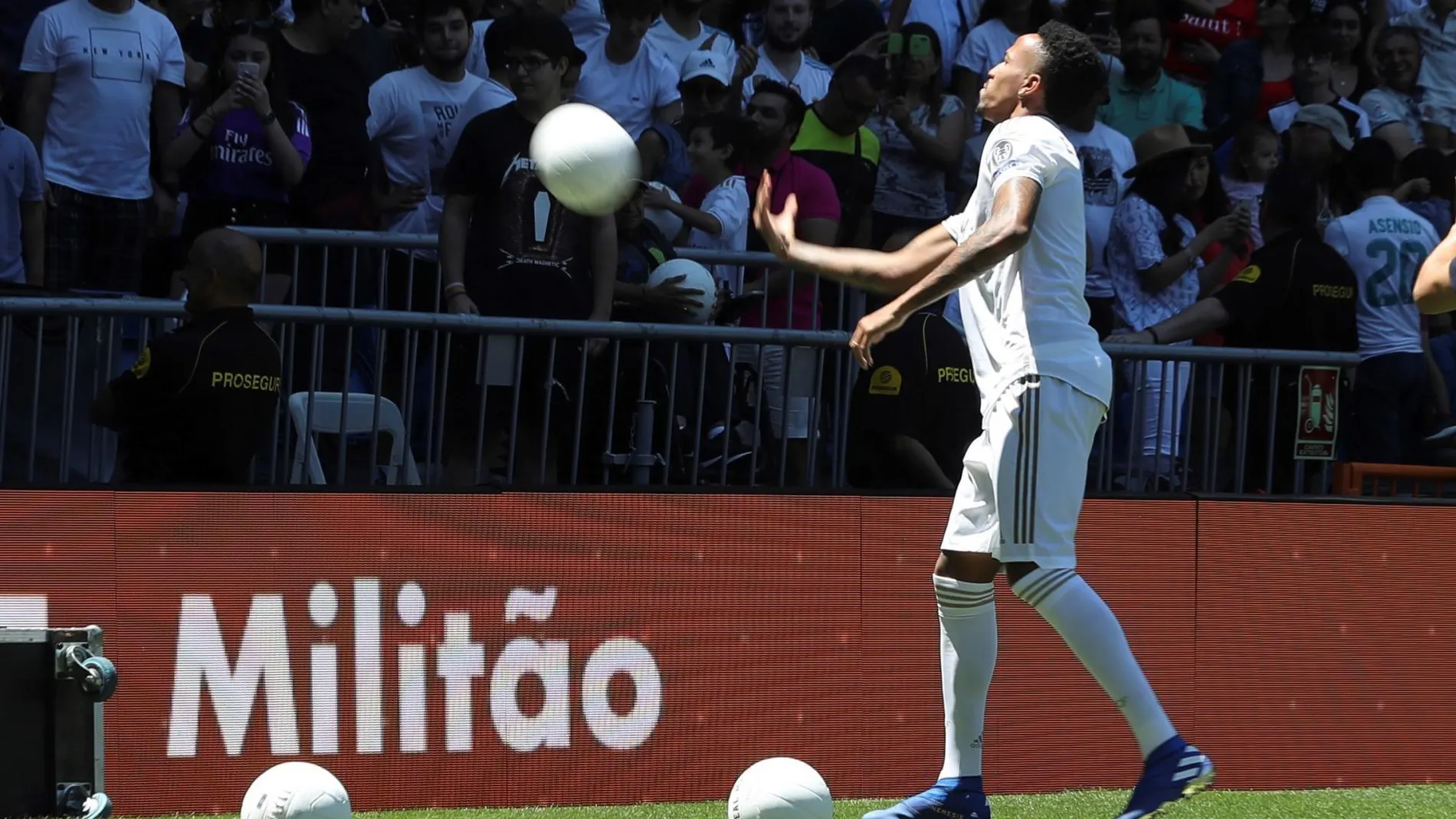 El defensa brasileño Eder Militao lanza balones a los aficionados del Bernabéu