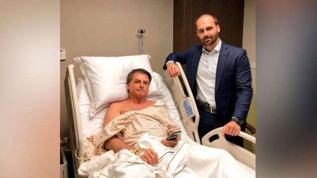 Jair Bolsonaro tras ser operado junto a su hijo Eduardo, que porta una pistola en la cintura/Twitter/@BolsonaroSP