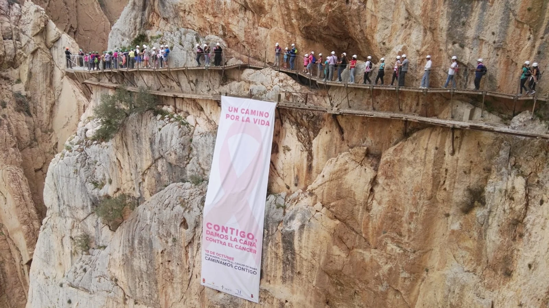 La lona gigante colocada en una de las paredes rocosas del desfiladero junto al balcón de cristal con un gran lazo rosa / Foto: La Razón