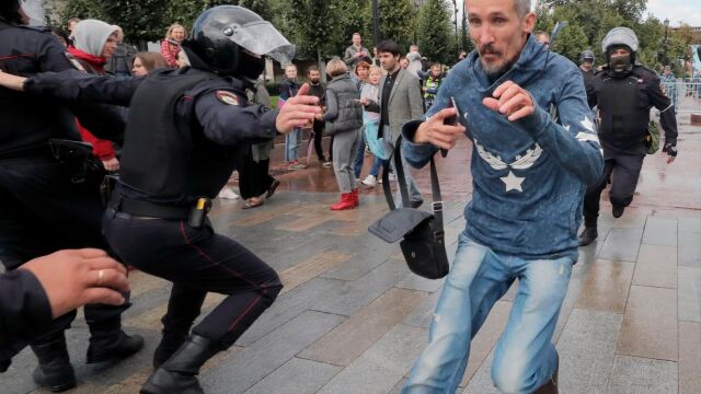 Varios agentes de seguridad tratan de atrapar a un manifestante