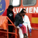 Un sanitario ayuda a un menor durante el desembarco de inmigrantes en Melilla