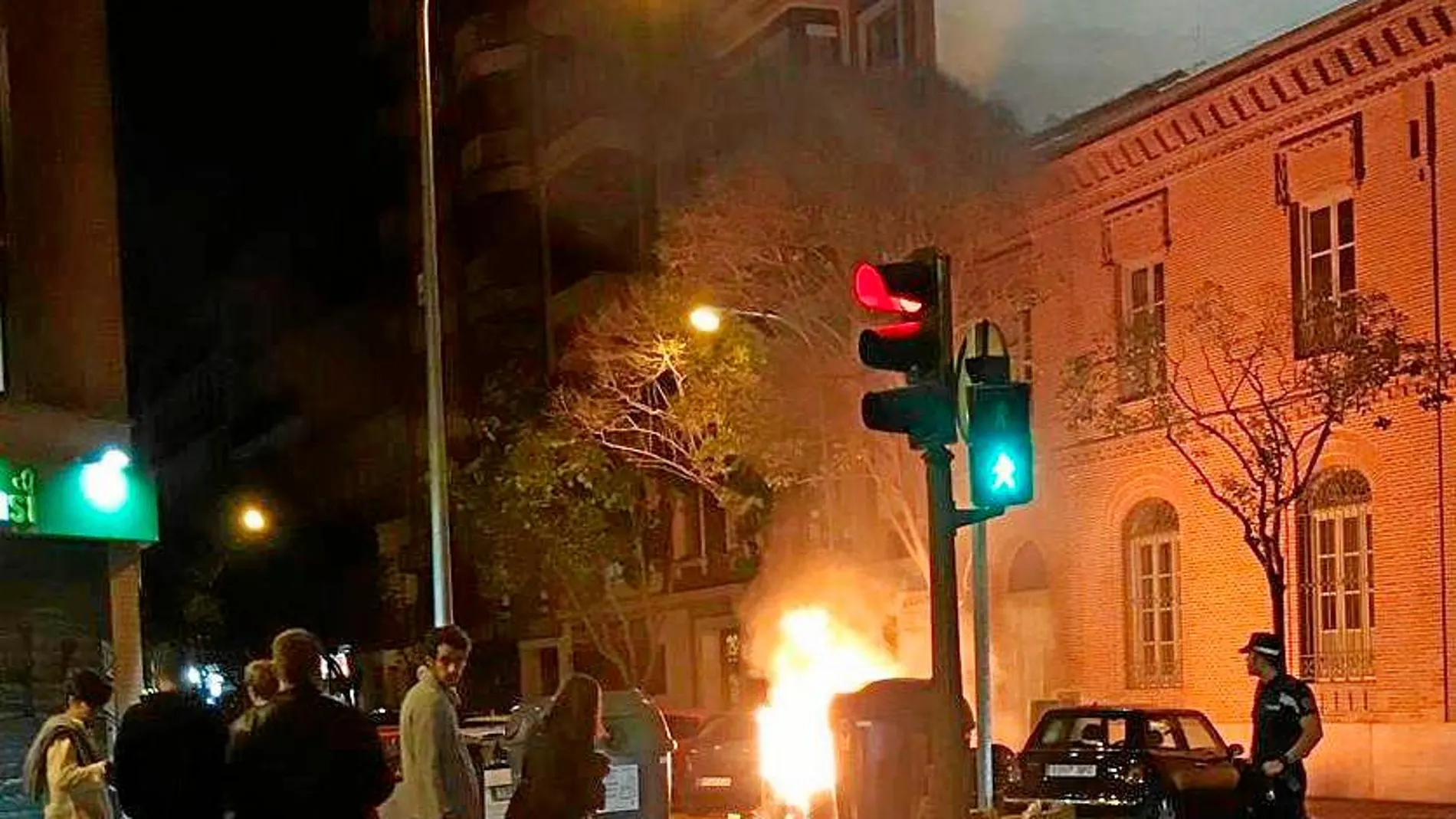 Los vecinos asisten atónitos a la quema de un contenedor en la calle Meléndez Valdés