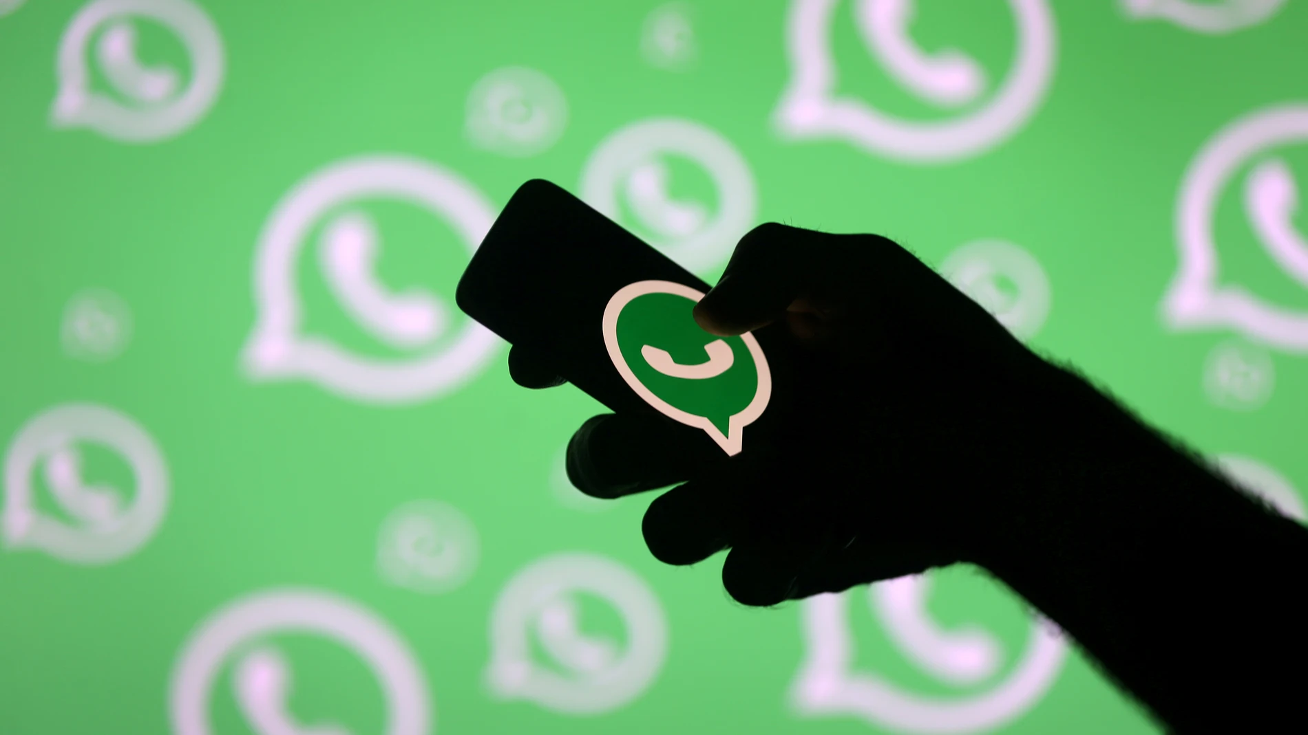 FILE PHOTO: A man poses with a smartphone in front of displayed Whatsapp logo in this illustration picture