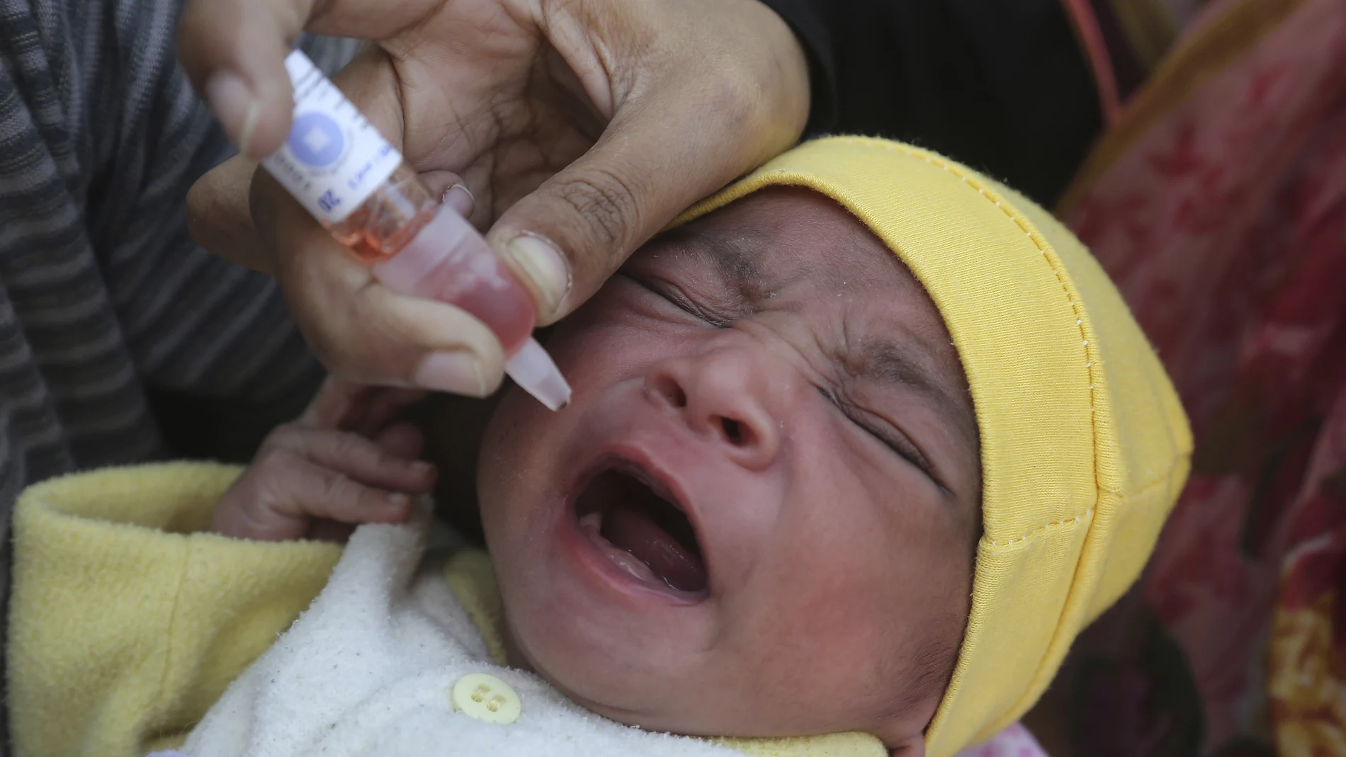 Una mujer vacunando a un bebé pakistaní contra la Polio