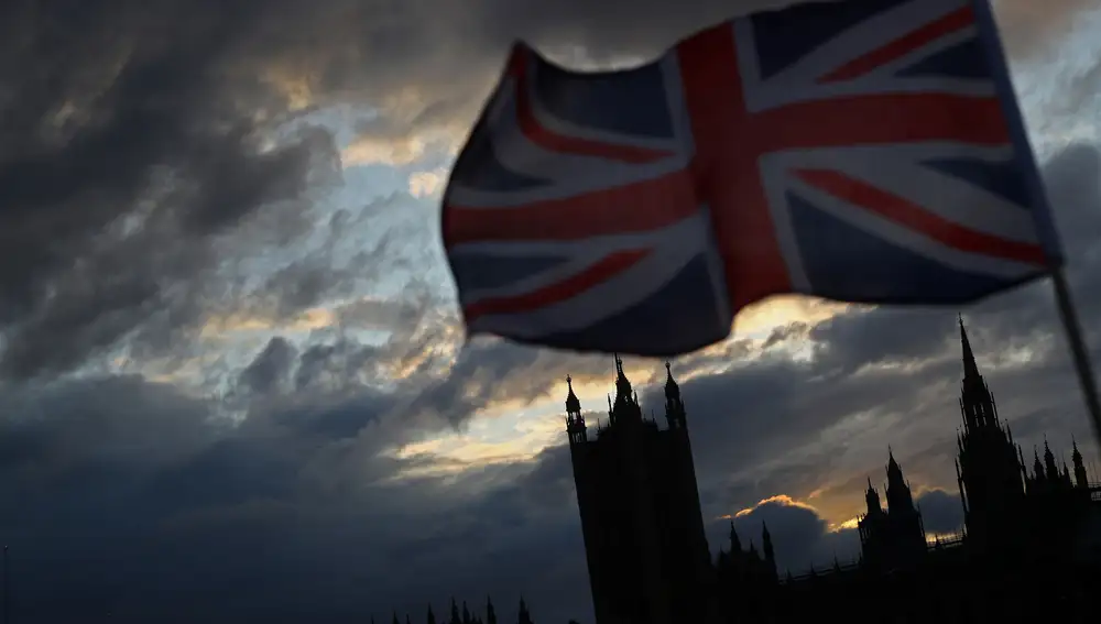 A Union Jack flag flutters in front of the Houses of Parliament in London