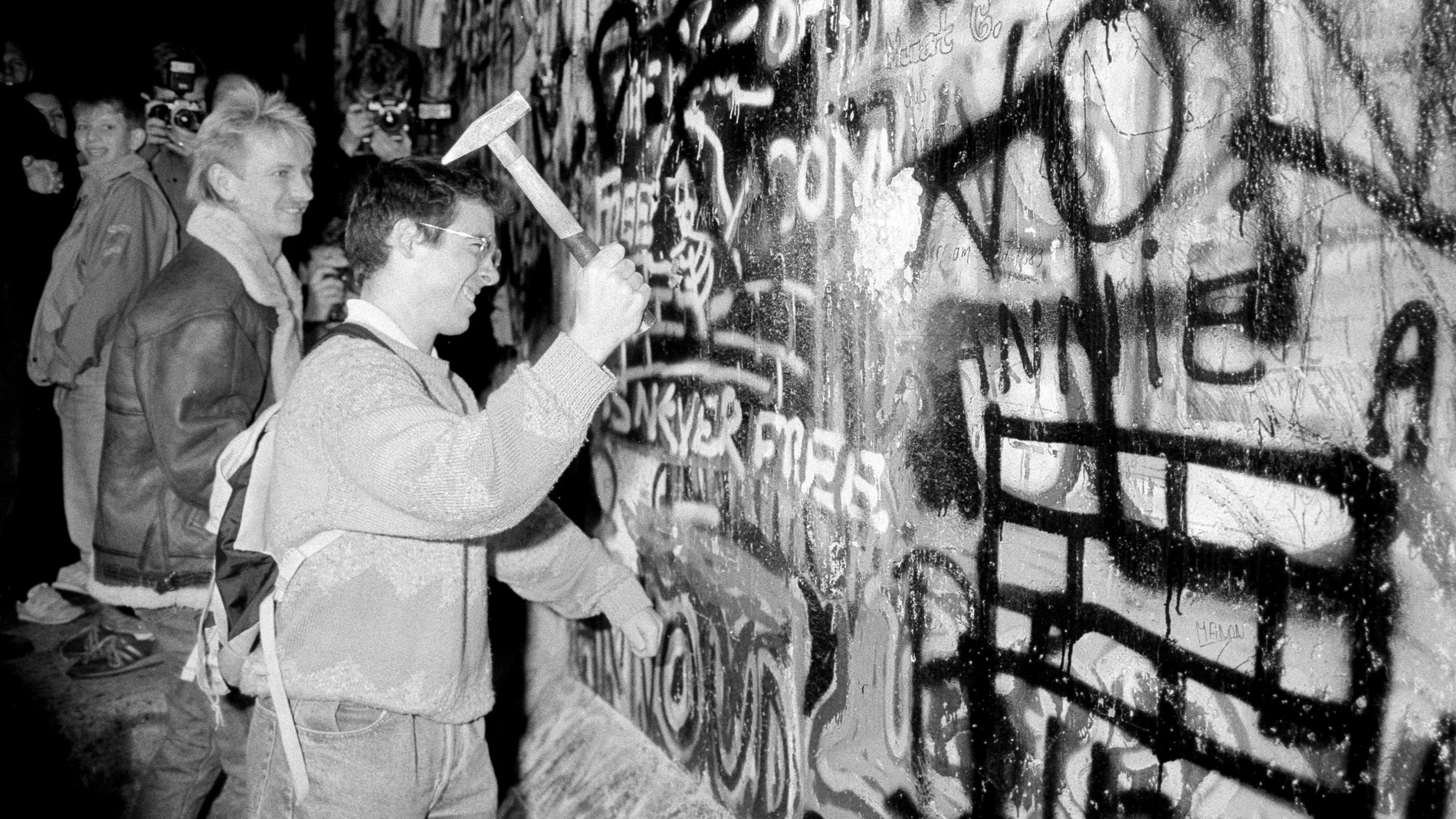 Un hombre golpea con un martillo el Muro de Berlín la histórica noche del 9 de noviembre de 1989