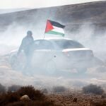 Un hombre ondea la bandera palestina entre gas lacrimógenos. EFE/ Abed Al Hashlamoun