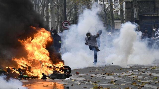 Un manifestante devuelve de una patada un bote de gas lacrimógeno durante las protestas hoy en París