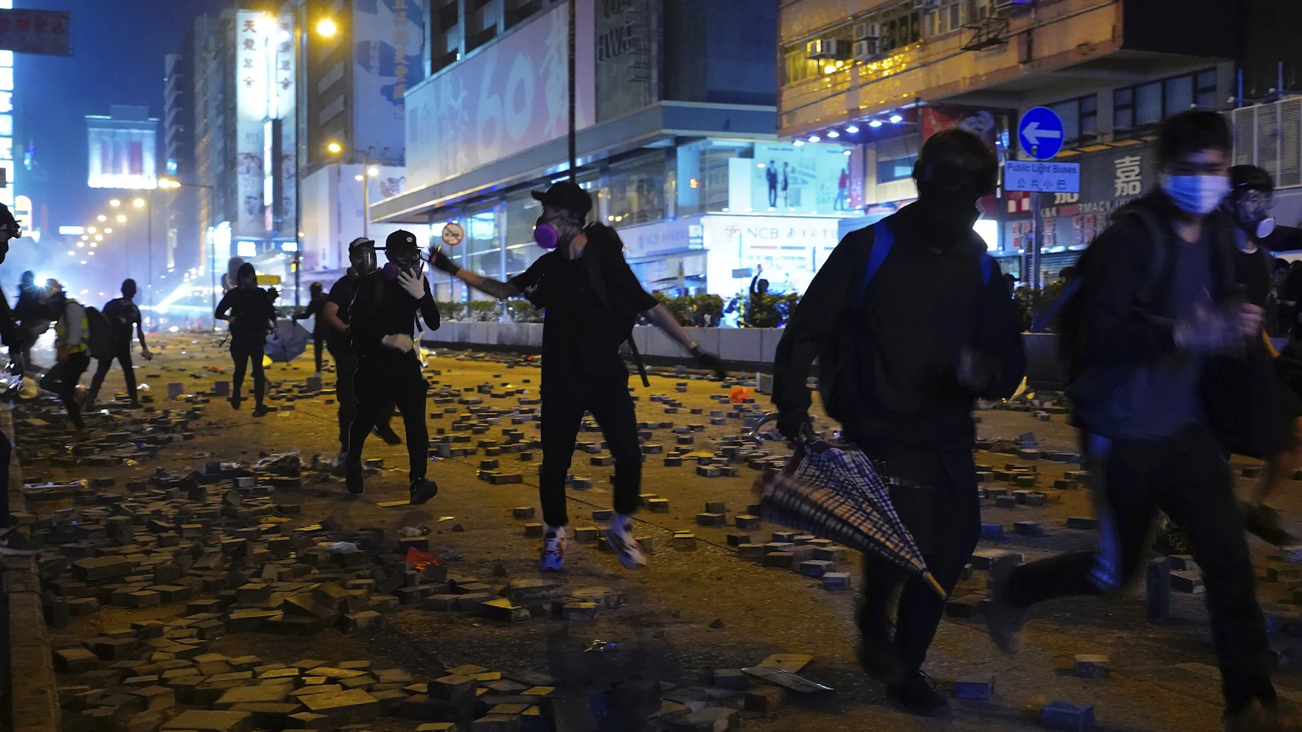 Protesters run along a street in the Kowloon area of Hong Kong, Monday, Nov. 18, 2019. As night fell in Hong Kong, police tightened a siege Monday at a university campus as hundreds of anti-government protesters trapped inside sought to escape. (AP Photo/Vincent Yu)