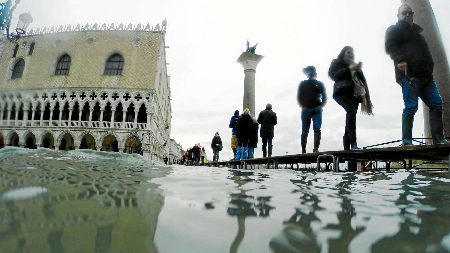 Gente caminando sobre las plataformas en Venecia, ayer, después de una nueva crecida del agua / Ap