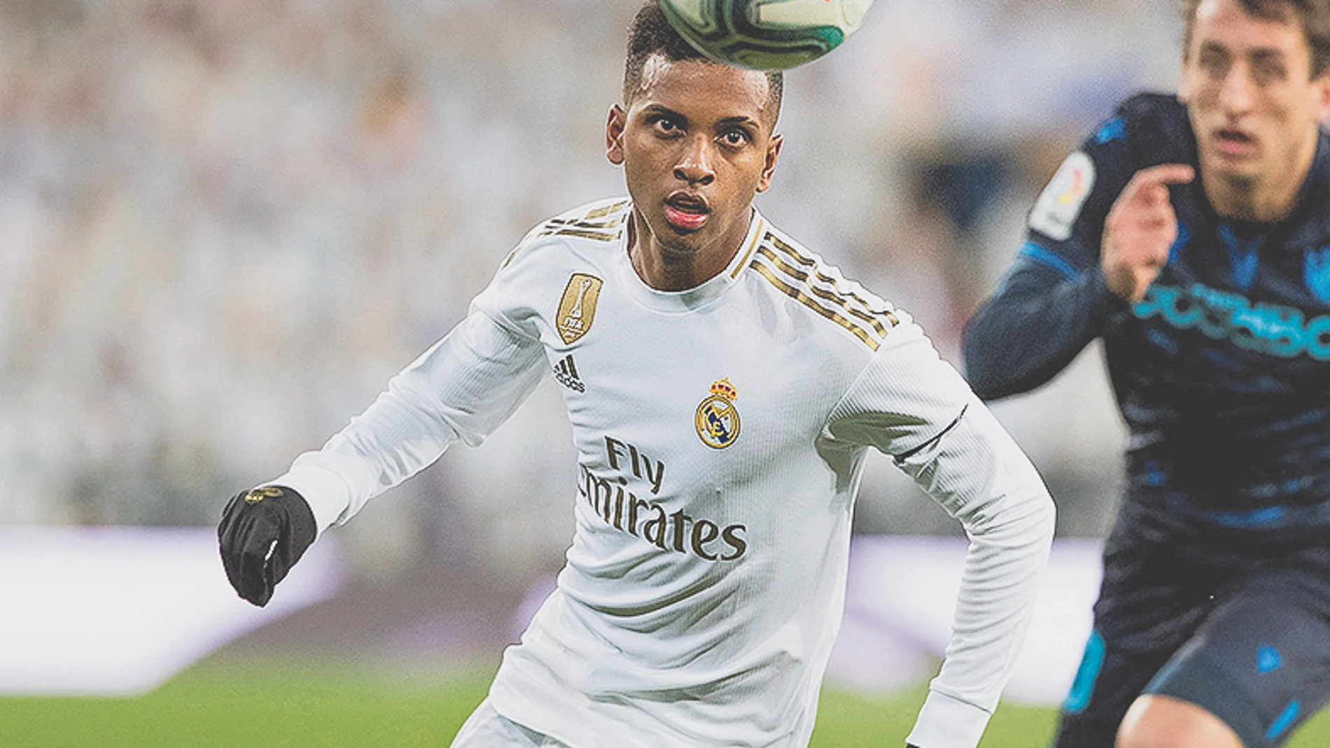 El delantero del Real Madrid Rodrygo (i) persigue el balón durante el partido ante la Real Sociedad, correspondiente a la décimo cuarta jornada de LaLiga Santander disputada en el Estadio Santiago Bernabéu.