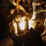 Algunos manifestantes tratan de apagar las llamas del hombre que intentó quemarse a lo bonzo. © AP Photo/Bilal Hussein)
