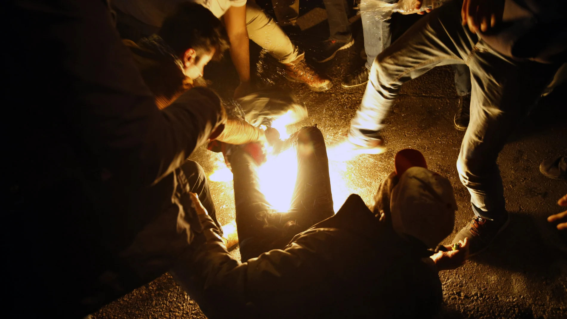 Algunos manifestantes tratan de apagar las llamas del hombre que intentó quemarse a lo bonzo. © AP Photo/Bilal Hussein)