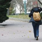 Una mujer caminando por la calle se protege del viento