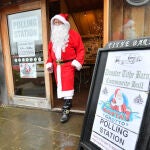 Un hombre disfrazado de Papá Noel sale de una estación electoral después de depositar su voto en Minehead, Reino Unido.