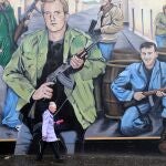 Una mujer camina bajo un mural en Belfast, Irlanda del Norte, para celebrar el 20 aniversario de la firma del acuerdo de paz del Viernes Santo. EFE/ Paul Mcerlane