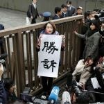 Victoria. La periodista japonesa sostiene un cartel en el que se puede leer "Victoria"
