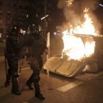 Police officers walk past a burning garbage container toward the end of a Catalan pro-independence protest outside the Camp Nou stadium in Barcelona, Spain, Wednesday, Dec. 18, 2019. Thousands of Catalan separatists protested around and inside Barcelona's Camp Nou Stadium during Wednesday's match against fierce rival Real Madrid. (AP Photo/Joan Mateu)