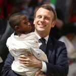 El presidente de Francia, Emmanuel Macron, sostiene a un niño durante la inauguración del "win win" de Agora en Koumassi, Abidjan, Costa de Marfil, 21 de diciembre de 2019.