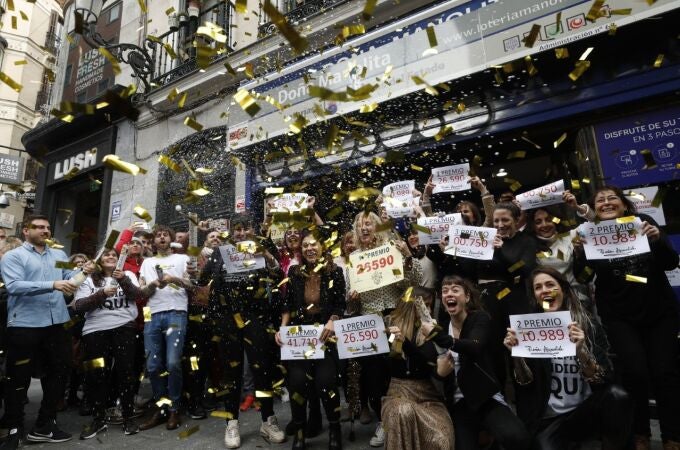 22/12/2019. Madrid. Los empleados de Doña Manolita posan con los carteles de todos los premios que se han vendido en el sorte de Navidad y celebran con algunos de los premiados. © Gonzalo Pérez