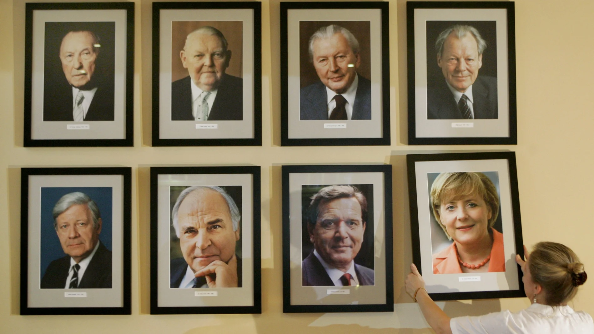 La gerente del restaurante Angelika Meixner coloca un retrato de la nueva canciller alemana, Angela Merkel, junto a fotos de sus predecesores en una pared en el restaurante 'Kanzlereck'