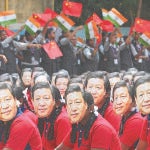 Varios estudiantes con una careta del presidente de China, Xi Jinping, en un congreso en India