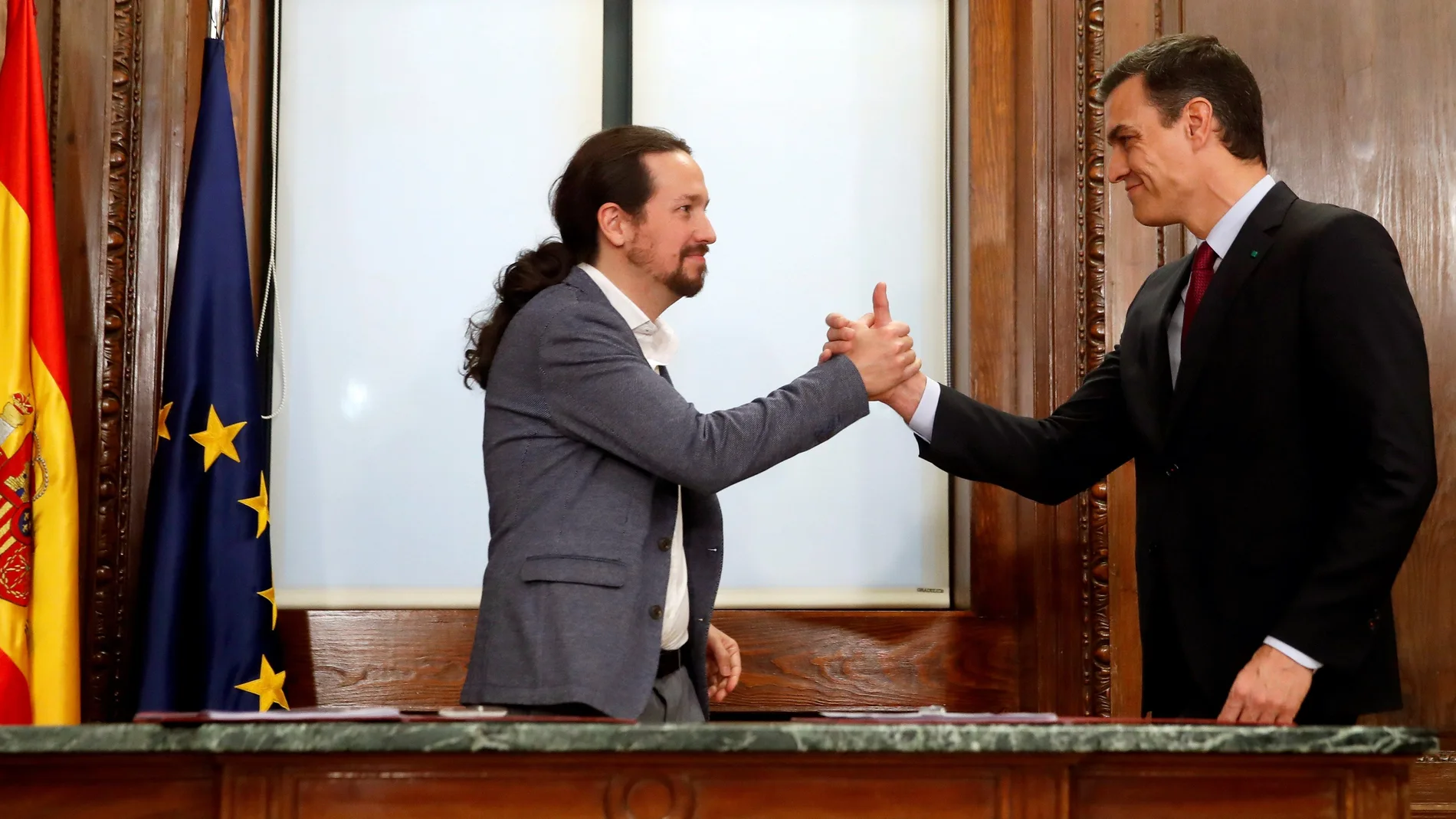 El candidato a la investidura, Pedro Sánchez (d), y el líder de Podemos, Pablo Iglesias (i), estrechan sus manos tras el acto de firma del acuerdo