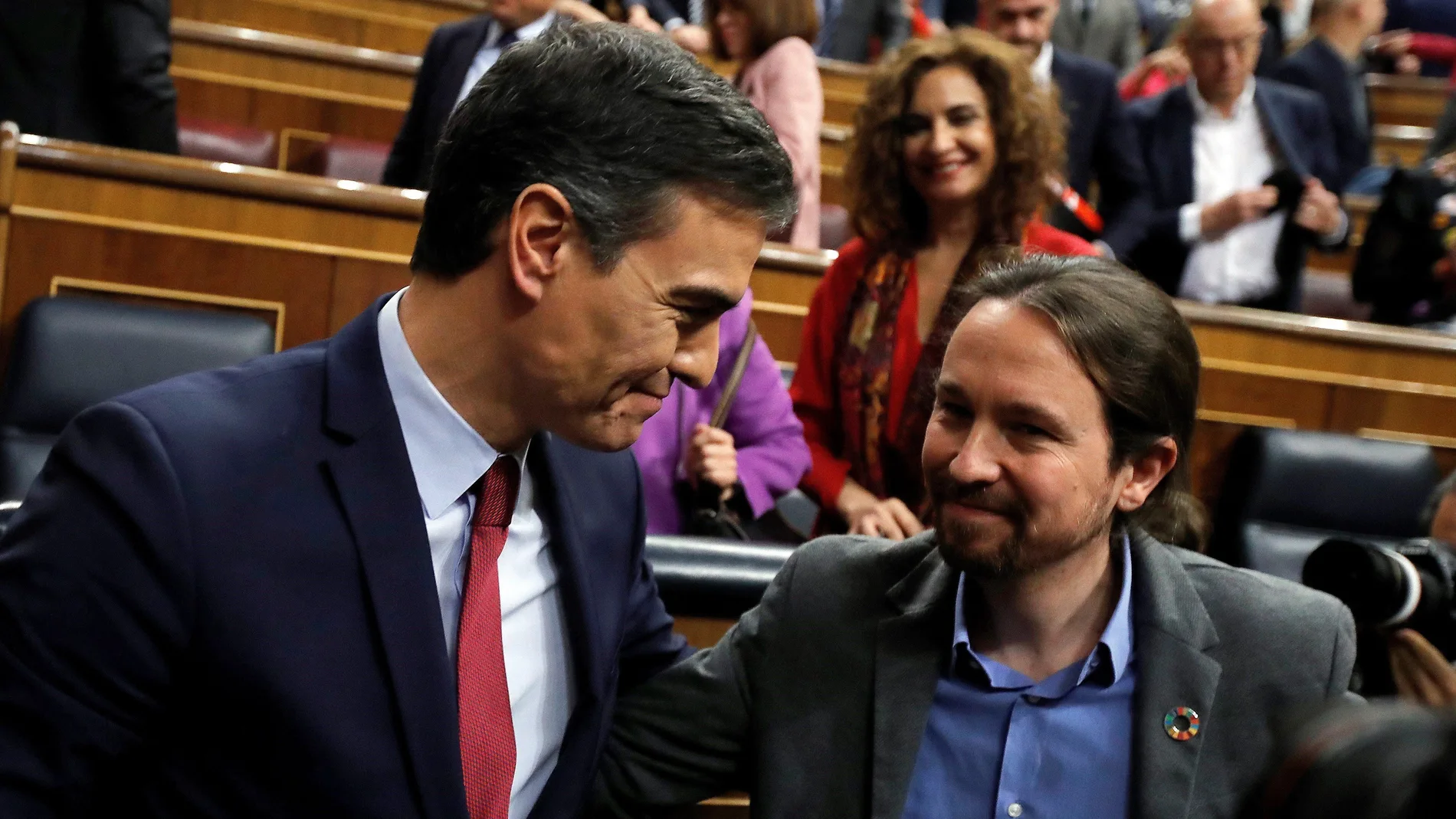 Pedro Sánchez, quien logró este martes la confianza del Congreso para un nuevo mandato como presidente del Gobierno, al lograr una estrecha mayoría de 167 votos a favor, 165 en contra y 18 abstenciones, es felicitado por el líder de Unidas Podemos, Pablo Iglesias (d). EFE/Juan Carlos Hidalgo