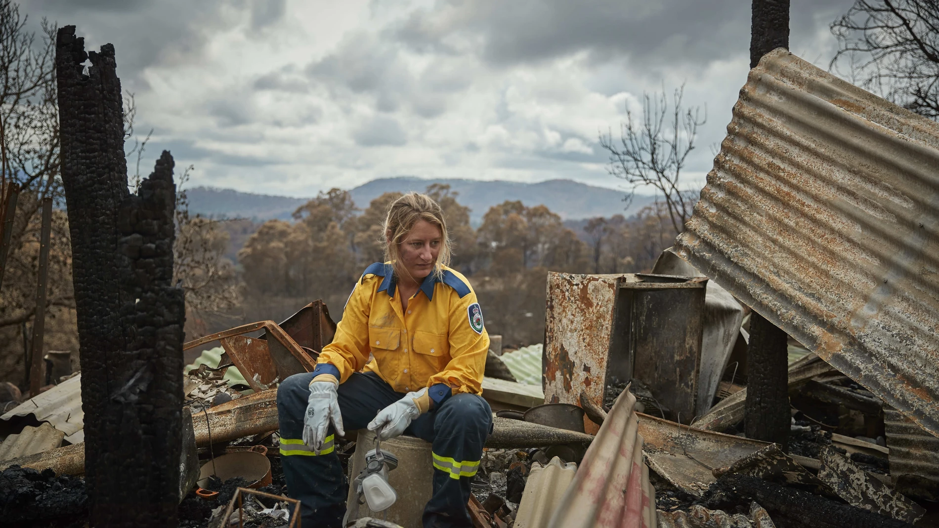 Una bombera voluntaria descansa en los restos de su casa en Verona, Australia