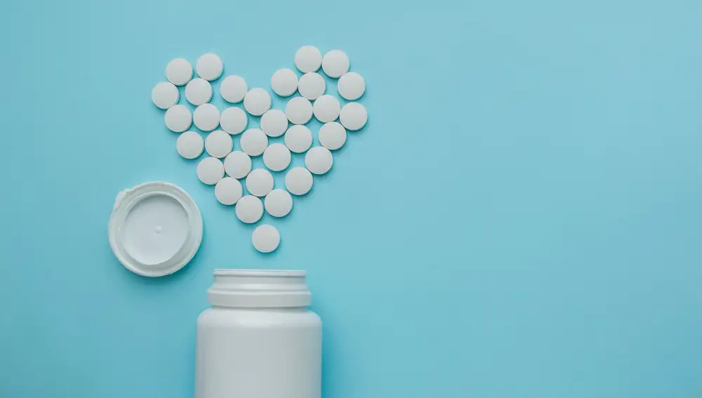 Medicines white, round heart shaped pills isolated on blue background.