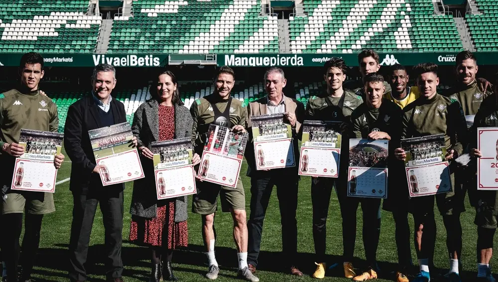 Parte de la plantilla del Real Betis Balompié y responsables de Coca-Cola posan en el césped del estadio de fútbol del Benito Villamarín este viernes en Sevilla