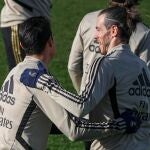 El centrocampista colombiano del Real Madrid, James Rodríguez (i) bromea con centrocampista galés Gareth Bale (d) durante el entrenamiento del equipo en la Ciudad Deportiva en Valdebebas, Madrid este viernes 17 de enero para preparar el partido contra el Sevilla en el Santiago Bernabéu correspondiente a la jornada 20 de LaLiga. EFE/Emilio Naranjo